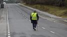 Un peatn equipado con chaleco reflectante cruza una carretera cerca de Santiago.