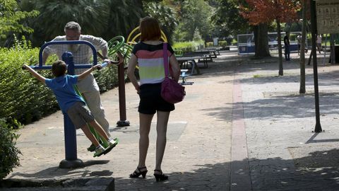 Un hombre mayor juega con un nio en un parque de Oviedo mientras disfruta del calor y el buen tiempo