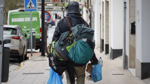 Un hombre sin hogar camina con sus pertenencias por una calle de Lugo.