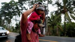 Un migrante hondure�o trata de cubrir de la lluvia a su hija mientras camina por una carretera de Guatemala en direcci�n a Mexico 