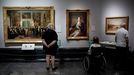Tres asistentes observan varias obras en el Museo del Prado, en Madrid. 