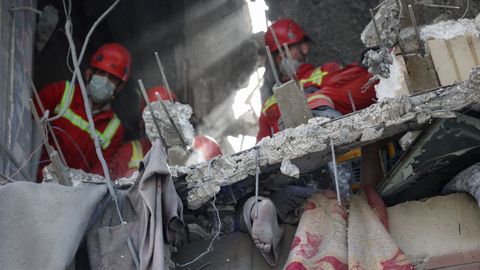 Equipos de rescate iran�es recogen un cuerpo en un edificio bombardeado en Teher�n.