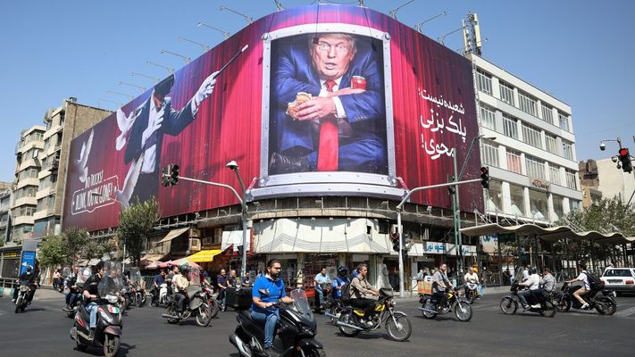 Un grupo de motoristas circulan por las proximidades de una lona contra Donald Trump, el presidente de Estados Unidos, en la capital del pa�s, Teher�n.