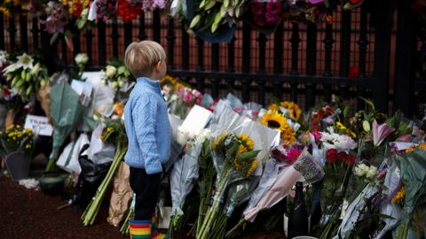Un ni�o observa los tributos florales a la reina.