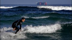 Un surfista, en la playa de Sab�n, cuando se alejaba el buque de carga