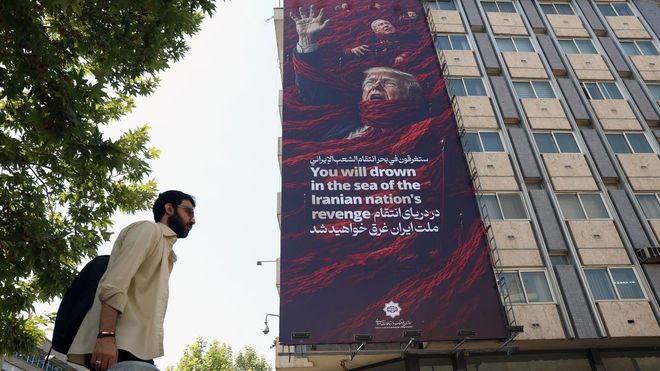 Un hombre pasa ante un mural en Teher�n que reclama venganza para los presidentes de Estados Unidos e Israel