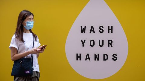 En Hong Kong, una mujer pasa por delante de un mural que anima a lavarse las manos