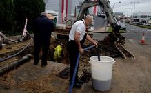 El due�o de El Gaucho D�az II llena un contenedor con agua turbia mientras los operarios trabajan.