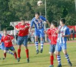 El local Sera despeja de cabeza una pelota entre dos rivales.