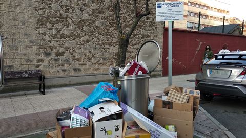 Basura en el exterior de los contenedores de la calle Lola Mateos (Marcos Peña Royo) de Oviedo. Un nuevo cartel avisa de la multa por realizar vertidos en la vía pública