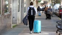 Un chica por la calle con una maleta.