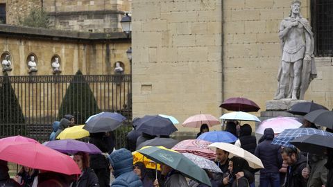 Turistas se protegen dela persistente lluvia en la plaza de la Catedral de Oviedo
