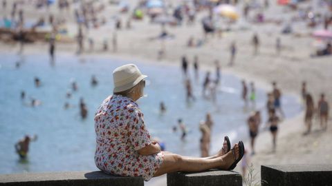 Una mujer toma el sol junto a la playa de Riazor.
