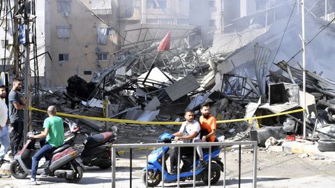 La gente pasa junto a un edificio destruido tras un ataque aéreo israelí en el distrito de Dahieh, en el sur de Beirut.