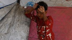 Un nio desplazado, que huy de la ciudad de Gaza, junto a una valla mientras descansa al borde de la carretera, en el centro de la Franja de Gaza este domingo.