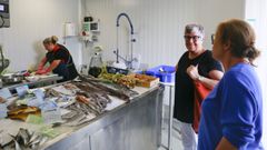 Elsa, de fondo, preparando el pescado, con dos clientas en A Ta Lonxa.