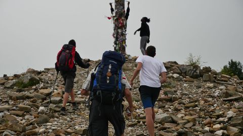 Varios peregrinos caminan junto a la cruz de Fierro