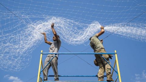 Dos ucranianos reparan la red anti drones cerca del Domb�s.