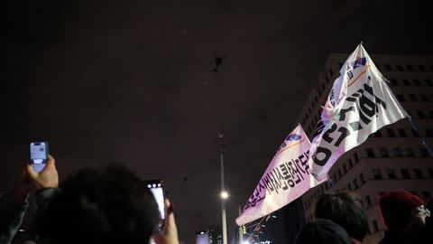 La gente agita pancartas mientras los helicpteros militares sobrevuelan Sel. 