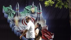 Una pareja iran pasa junto a una enorme pancarta antiisrael con imgenes de misiles, en Tehern.
