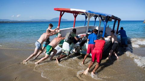 Turistas ayudan a empujar un bote que qued atrapado en la playa Alicia en Sosa, en la provincia de Puerto Plata (Repblica Dominicana)