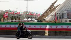 Dos hombres pasan en moto ante misiles ubicados en una plaza de Teher�n