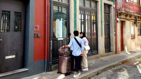 Dos viajeros en una calle de Oporto, junto a la entrada de un piso turístico.