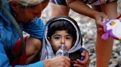 Una voluntaria ofrece agua a un ni�o sirio exhausto reci�n desembarcado en Lesbos.