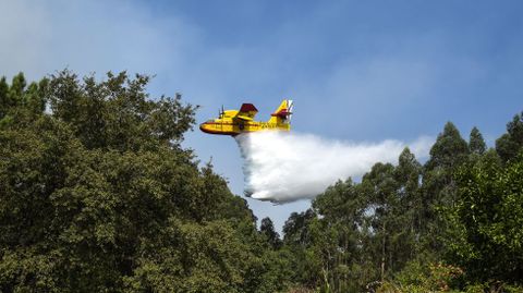 Un hidroavin echando agua para extinguir un foco de fuego declarado cerca de las viviendas de Vilar, en Vilaboa