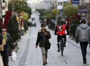 Tres usuarias buscan cobertura de wifi en la calle peatonal de O Calvario