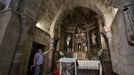 El sacristán de Campo Lameiro señala el retablo de la iglesia. Las pinturas están detrás en las paredes de piedra