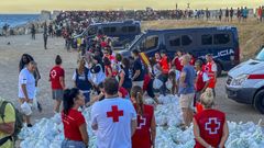 Miembros de la Cruz Roja reparten bolsas de comida a los inmigrantes en una playa de Ceuta.