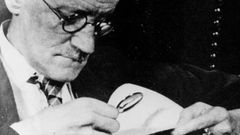 El escritor James Joyce examinando con lupa un documento.