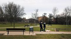 Dos chicos pasean con sus perros por un camino del paseo fluvial, en la zona del parque de Covas