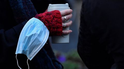 Una mujer con la mascarilla colgada de la muñeca
