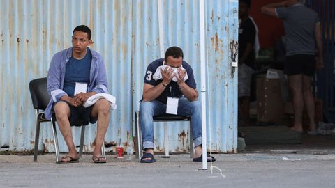 Migrantes rescatados esperan noticias en el puerto de Kalamata.