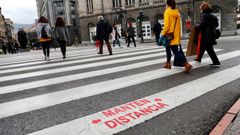 Varias personas cruzan un pase de peatones con un aviso de recomendaci�n de distanciamiento social pintado por el Ayuntamiento de Oviedo como forma de frenar la pandemia del coronavirus.