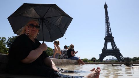 Cierre parcial de la torre Eiffel.Una mujer se refresca y se protege del sol a los pies de la torre Eiffel, que se cerró parcialmente por la canícula extrema.