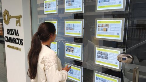 Imagen de archivo de una mujer mirando los carteles de viviendas en alquiler en una inmobiliaria de A Coru�a