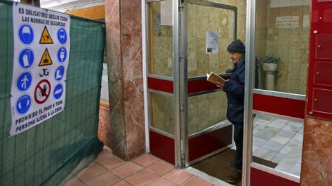 Armando Guerra, con su inseparable libro, saliendo del edificio en el que lleva casi tres décadas y del que es el último inquilino.