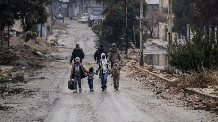 Una madre y sus hijos de camino a su casa en Alepo, este domingo
