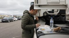 Un camionero aprovecha un espacio externo del veh�culo para comer en el pol�gono de San Cibrao, en Ourense