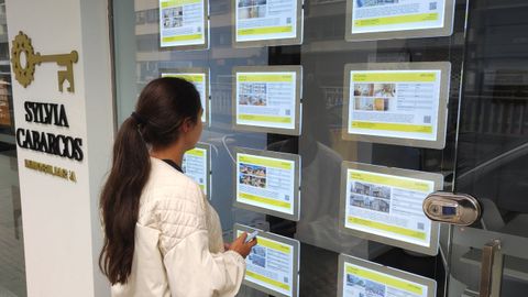 Una mujer consulta los precios de pisos en alquiler en una inmobiliaria gallega.