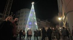Una pareja pasa sonriente frente al �rbol luminoso de 14 metros de la plaza de Espa�a este viernes unos minutos despu�s del encendido del alumbrado navide�o