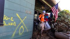 Un voluntario ayuda a los habitantes de una casa destrozada por la tormenta Helena en Carolina del Norte