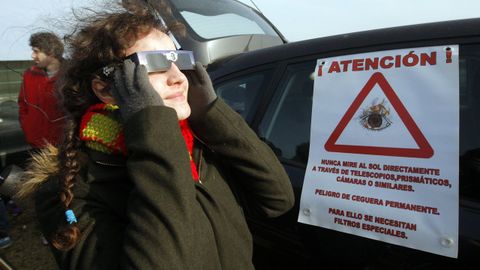 Una mujer, cuidando sus ojos con unas gafas homologadas, disfruta de un eclipse.