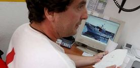�ngel, uno de los dos miembros de la Cruz Roja que participaron en el rescate, muestra la foto del pesquero �Encarnita Dous�.