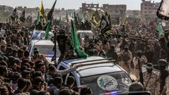 Combatientes de Hams controlan a la multitud durante la entrega de los rehenes como parte del intercambio de prisioneros entre Israel y Hams.