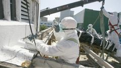 Operarios con trajes de proteccin para retirar elementos con amianto de una vivienda en Ferrol. 