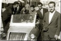 Un grupo de personas posan divertidas alrededor de un Biscuter, en la plaza de Santa Ana de Chantada, en 1960